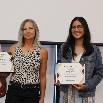 Two women holding completion certificates smiling at the camera.