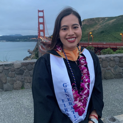 A Hispanic woman in graduation gown with the Golden Gate Bridge in the background.